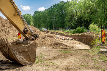 an excavator bucket near construction site, New fiber glass water pipeline in trench. Replacement...