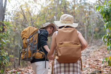 Happy LGBT lesbian couple travel enjoy hiking with backpack in forest trail