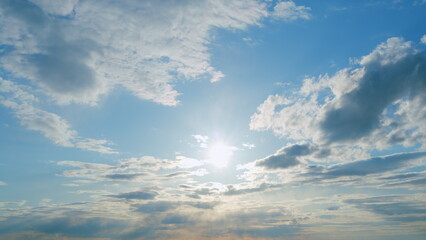 Beautiful sunny blue sky with bright sun light shining through white clouds. Timelapse.