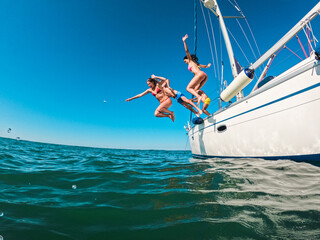 Happy friends diving from sailing boat into the sea - Travel and summer vacation concept - Soft focus on blond girl face