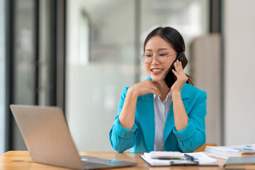 Asian businesswoman modern professional talking with client on the phone with a confident demeanor...