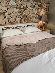 there is a large bed in the room, made with bed linen, and a lamp on the bedside table
