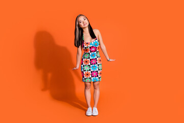 Full size photo of good mood woman with dyed hairstyle wear print stylish dress standing like doll isolated on orange color background