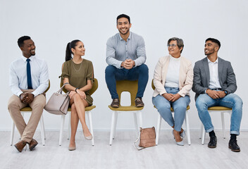 Job interview, waiting and candidates with man on chair for recruitment, diversity and unique with white background. Male person, applicants and happy with smile for pride, success and opportunity