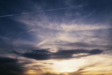 Dramatic sunset sky with airplane trails and whale shaped cloud