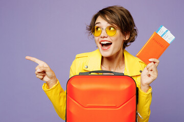 Traveler woman wear yellow casual clothes glasses hold bag point finger aside isolated on plain...