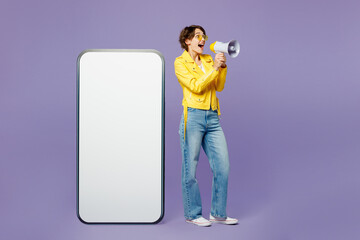 Full body young woman she wears yellow shirt white t-shirt casual clothes glasses big huge blank screen mobile cell phone smartphone with area scream in megaphone isolated on plain purple background.