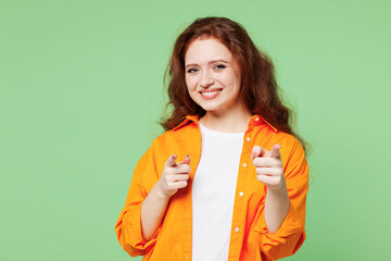 Young leader confident smiling fun ginger woman she wear orange shirt white t-shirt casual clothes point index finger camera on you isolated on plain pastel light green background. Lifestyle concept.
