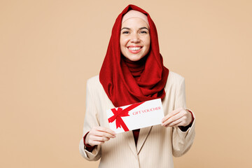 Young Arabian Asian Muslim woman wears red abaya hijab suit clothes hold gift certificate coupon...
