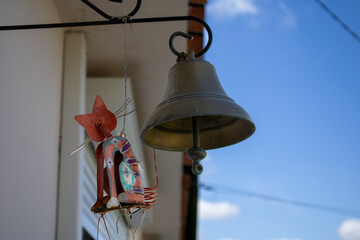 Ancienne cloche à l'entrée d'une maison, à côté d'un chat en métal.