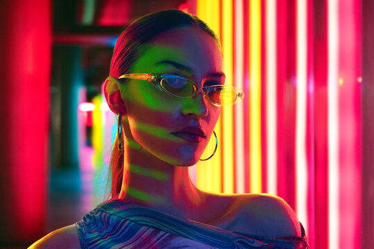 Neon nights portrait of young, beautiful, cool attitude woman, with sunglasses posing in dynamic, vibrant lights. Concept of youth, beauty, fashion and style, modern lifestyle. Ad - Powered by Adobe