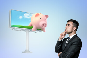 Man contemplating piggy bank billboard