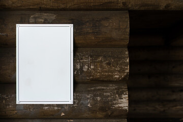 empty white sign mounted on the exterior wall of a logwood lean-to shelter