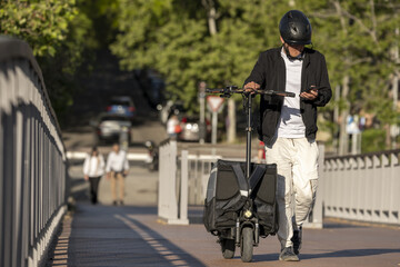A deliveryman from an urban delivery app with his skateboard and black delivery bag