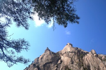 mountain peaks against a blue sky with green tree branches in the foreground. mountains in south korea. hiking korea