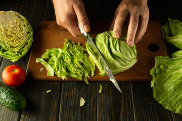 Chef hands with a knife while cooking on a kitchen black table. Delicious salad for breakfast with...