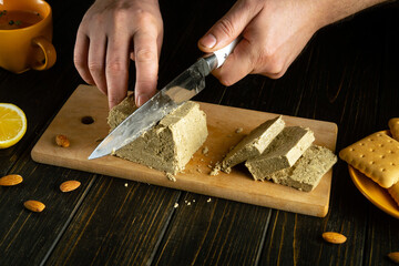 Making a sweet dessert from halva and lemon. Chef hands close-up with a knife while preparing breakfast on the kitchen table.