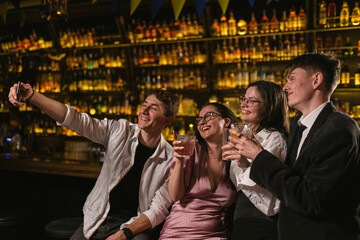 Stylish visitors pose for camera in trendy restaurant in evening. Cozy place near bar counter with...