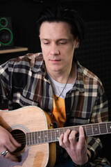 Obraz premium The man with black hair plays the guitar and sings into the microphone.