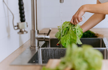 cleaning vegetable by water, Closeup of a young girl washing vegetables in kitchen.