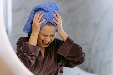 Young beautiful woman screaming and wearing shower towel after bath. Crazy and scared girl holding...