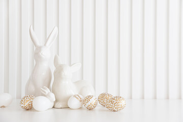 Easter rabbits figurines and eggs on white background. Easter celebration concept. Copy space. Front view - 809834629