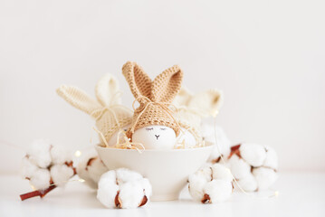 Easter eggs in crochet knitted hats with rabbit ears in nest. Easter celebration concept - 809834646