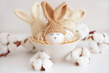 Easter eggs in crochet knitted hats with rabbit ears in nest. Easter celebration concept - 809834665
