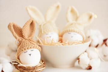 Easter eggs in crochet knitted hats with rabbit ears in nest. Easter celebration concept - 809834666