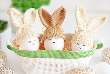 Easter eggs in crochet knitted hats with rabbit ears in nest. Easter celebration concept - 809834699