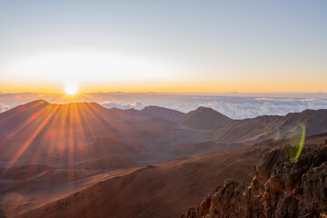 Sunrise shines over the Haleakala Volcano Mountains above clouds and the sky Maui, Hawaii