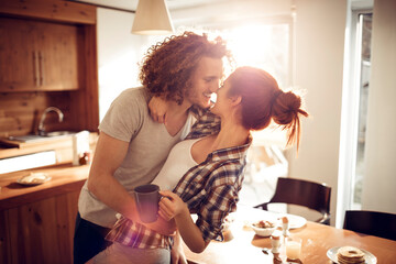 Happy couple embracing and kissing in sunny kitchen