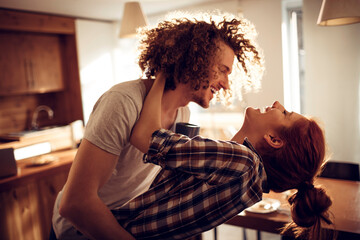 Happy couple embracing and kissing in sunny kitchen