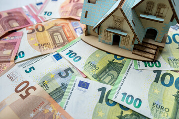toy house with a roof on euro banknotes as background