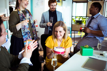 Office birthday celebration with colleagues enjoying cake and champagne