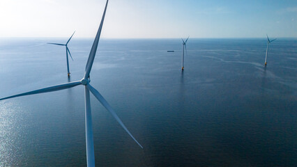 A group of majestic wind turbines stand tall in the ocean, their blades gracefully turning in the...