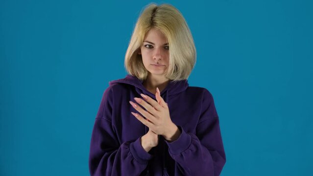 Girl rubs hands together putting hood on head to warm up. Teenage lady tries to stay cozy in cold weather looking for warmth