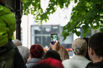 Man  photographing a street festival with camera phones. Young man taking photo of events using mobile phone . Rear view - Powered by Adobe