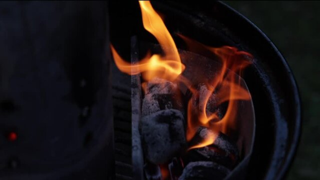 inquadratura in primo piano del fuoco che brucia le carbonelle, all'interno di una griglia