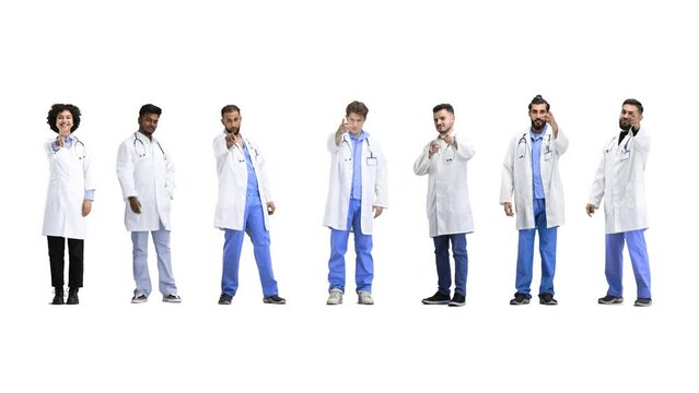 A group of doctors, in full height, on a white background, points forward