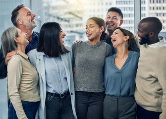 Business people, hug and laughing in office for team building, diversity and cooperation. Employees, together and solidarity in partnership at workplace, talk and funny joke or humor in conversation