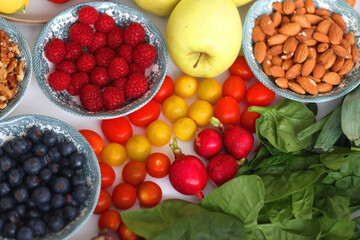 Apples, lemons, bananas, berries, carrots, leek, tomatoes, radishes, spinach and various nuts on...