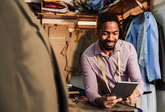 Portrait of male fashion tailor in his workshop using tablet.