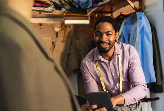 Portrait of male fashion tailor in his workshop using tablet.