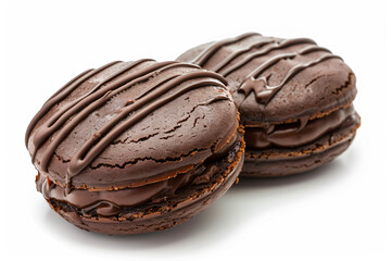 two chocolate macarons with chocolate frosting on a white surface