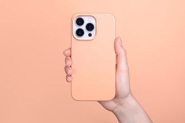 iPhone 15 pro in female hand in fuzz peach silicone cover isolated on 2024 pantone color of the...