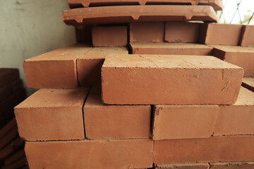 Stack of red clay bricks, construction material for building a house. Close up view