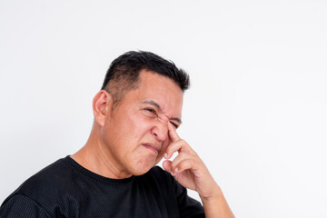 Image of a middle aged Asian man expressing discomfort while rubbing his irritated eyes, isolated on a white background.