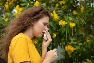 Portrait of beautiful young allergic woman is suffering from pollen allergy or cold on natural...