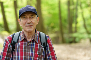 Portrait of senior man with backpack in the forest, looking at camera